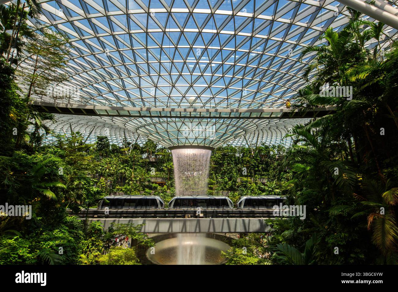 Aeroporto Jewel Changi di Singapore, lo Skytrain passa davanti al maestoso Rain Vortex, una miscela perfetta di movimento, design e serenità. Foto Stock
