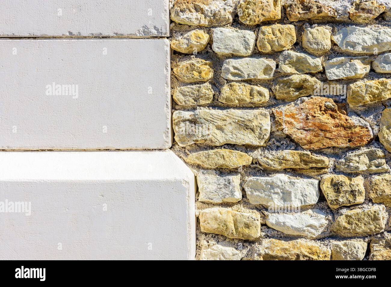 Nuovi blocchi di pietra calcarea adiacenti a vecchie pietre locali di dimensioni casuali in un muro ricostruito - Francia centrale. Foto Stock