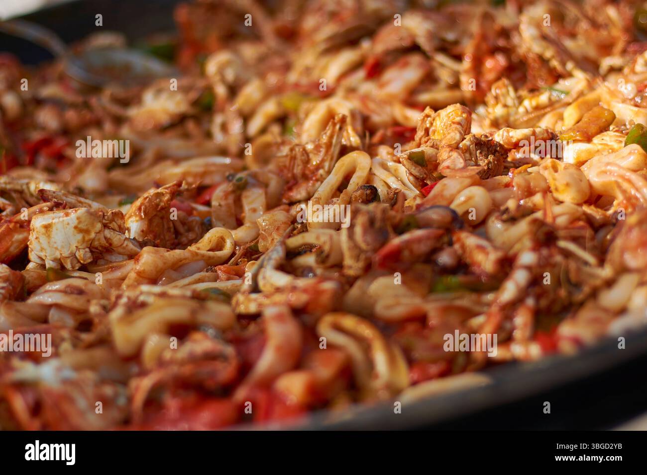 Primo piano di una deliziosa paella di pesce, con gamberi, calamari, granchi e verdure in una salsa ricca e saporita Foto Stock