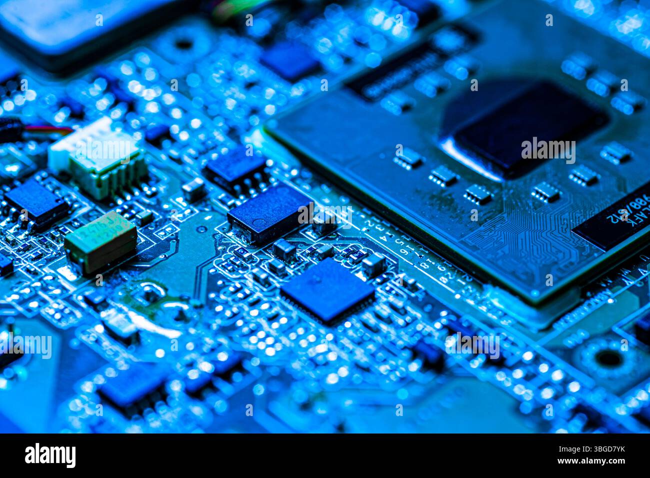 Milano, Italia 1 gennaio 2025: Circuito elettronico con cpu e componenti inondati di luce blu, che rappresenta la digitalizzazione e la tecnologia moderna Foto Stock