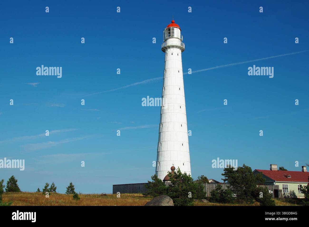 Faro bianco con cima rossa sulla costa sotto il cielo azzurro Foto Stock