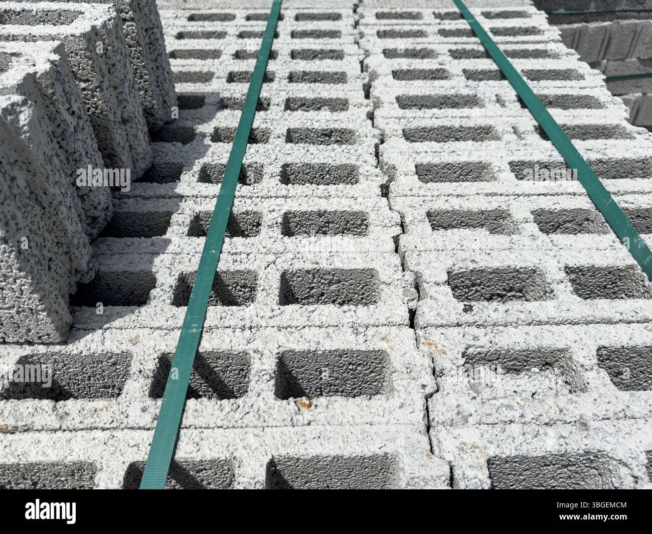 Blocchi di calcestruzzo cellulare impilati visti da un angolo con cinghie verdi per il fissaggio. Adatto per costruzioni, sfondi industriali e design. Foto Stock