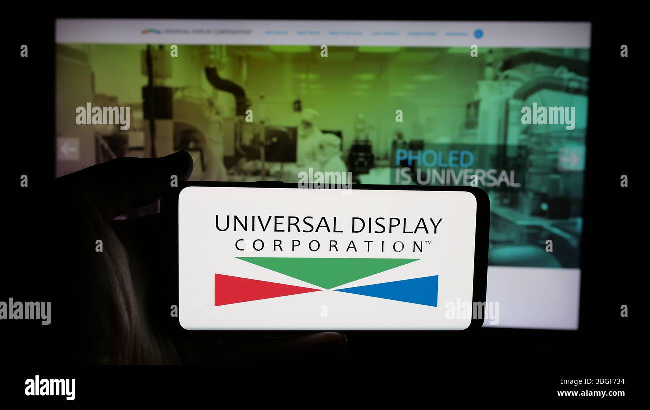 Stoccarda, Germania - 01-31-2025: Persona che tiene il cellulare con il logo della società americana OLED Universal display Corporation sullo schermo Foto Stock