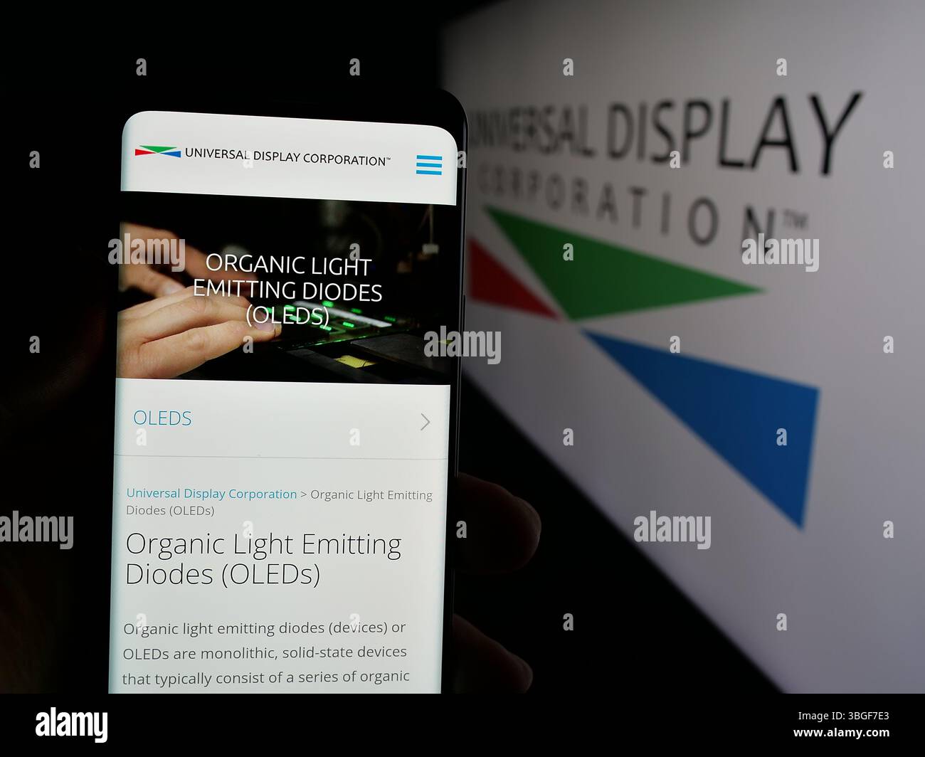 Stoccarda, Germania - 01-31-2025: Persona con smartphone con pagina Web della società statunitense OLED Universal display Corporation sullo schermo con logo. Foto Stock