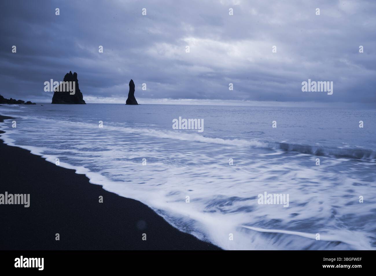 Il mare di basalto Reynisdrangar si staglia al largo della spiaggia nera di Reynisfjara presso il villaggio costiero di Vík nell'Islanda meridionale all'alba Foto Stock