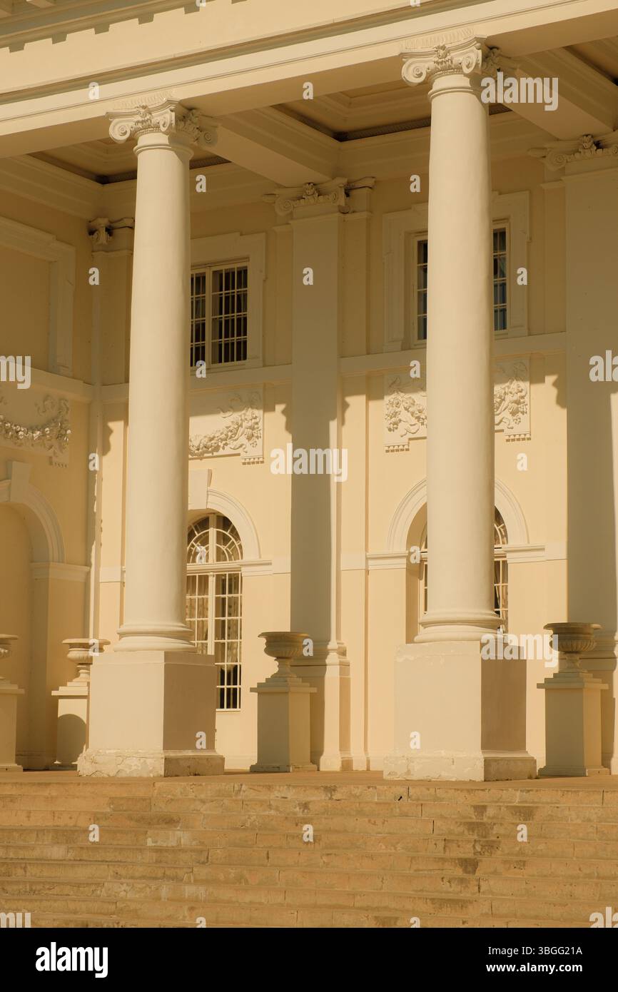 Primo piano di una facciata neoclassica del palazzo con alte colonne bianche, finestre ad arco e decorazioni ornamentali in stucco. Foto Stock