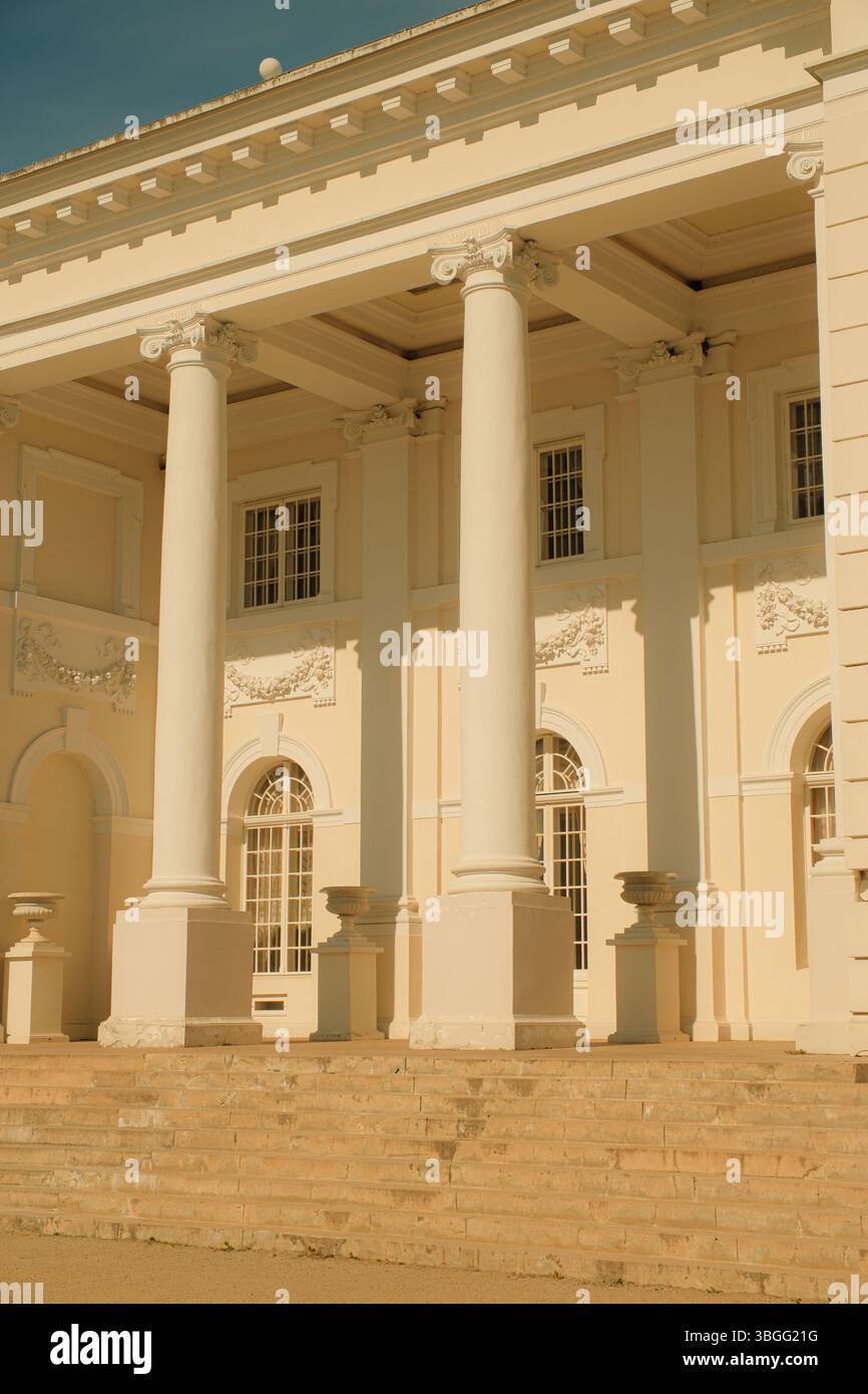 Primo piano di una facciata neoclassica del palazzo con alte colonne bianche, finestre ad arco e decorazioni ornamentali in stucco. Foto Stock