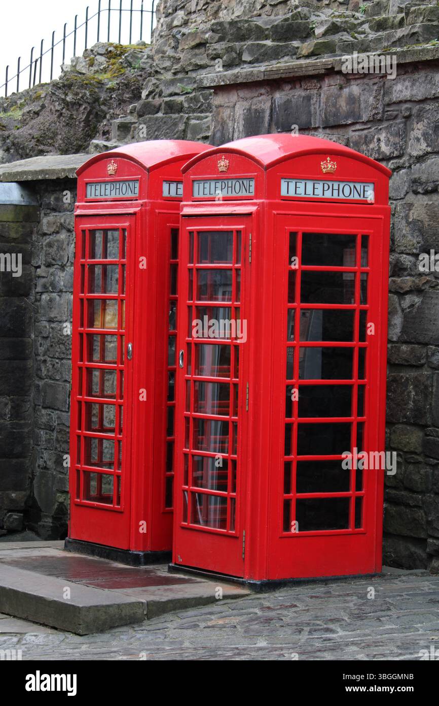 Tre iconiche cabine telefoniche rosse britanniche si trovano accanto a un muro di pietra a Edimburgo, Scozia, a simboleggiare il fascino vintage e il patrimonio di strada del Regno Unito. Foto Stock Tre iconiche cabine telefoniche rosse britanniche si trovano accanto a un muro di pietra a Edimburgo, Scozia, a simboleggiare il fascino vintage e il patrimonio di strada del Regno Unito. Foto Stock