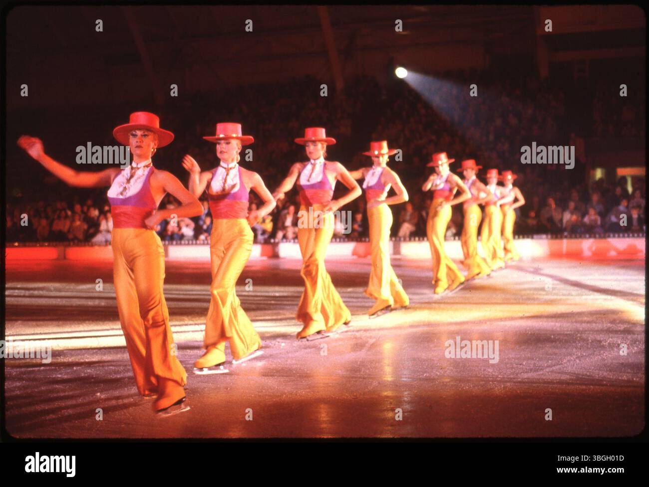 Nel 1980, una linea di pattinatori di figura vestiti con pantaloni gialli, top rosa e cappelli rossi esegue una routine di danza all'Ohio State Fairground Coliseum durante lo spettacolo Ice Follies and Holiday on Ice. L'evento combina costumi teatrali, pattinatori vincitori della medaglia olimpica e personaggi di Sesame Street. Foto Stock