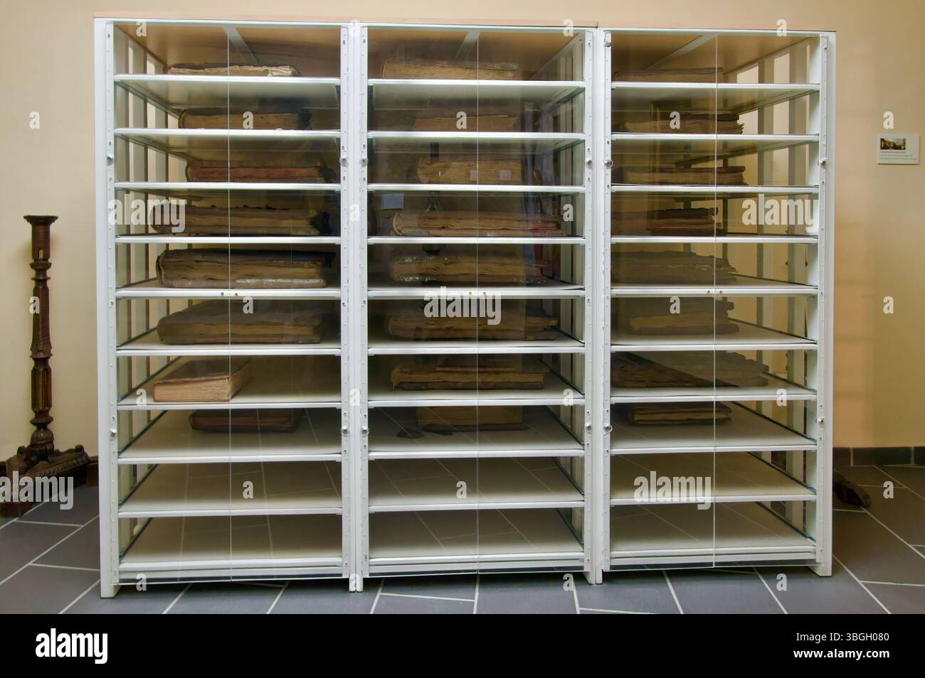 Scaffalature metalliche di archivio con porte in vetro contenenti manoscritti medievali sovradimensionati Co-Cattedrale di Santa María Cáceres Estremadura Spagna Europa Foto Stock