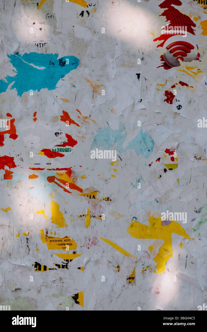 Una bacheca resistente agli agenti atmosferici con frammenti di carta colorati e poster strappati, creando uno sfondo strutturato e astratto. Strati di carta grunge frammentati Foto Stock