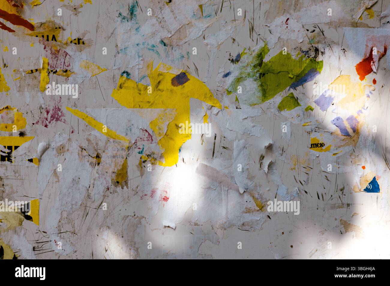 Una bacheca resistente agli agenti atmosferici con frammenti di carta colorati e poster strappati, creando uno sfondo strutturato e astratto. Strati di carta grunge frammentati Foto Stock