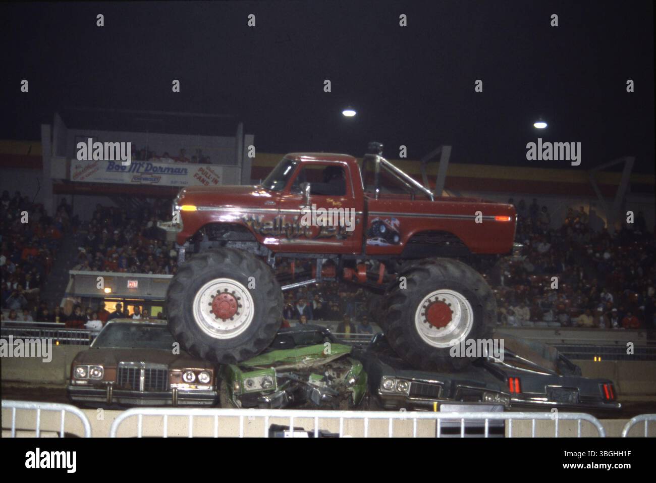 Il monster truck Walkin Tall viene mostrato schiacciando le auto più piccole davanti a un pubblico. L'evento si è svolto nell'ambito di uno show promozionale per Bob McDorman Chevrolet, dove uno striscione con la scritta "Welcome Pull-in Fans" è visibile negli stand. Il furgone era di proprietà di Tom Beitz. Foto Stock