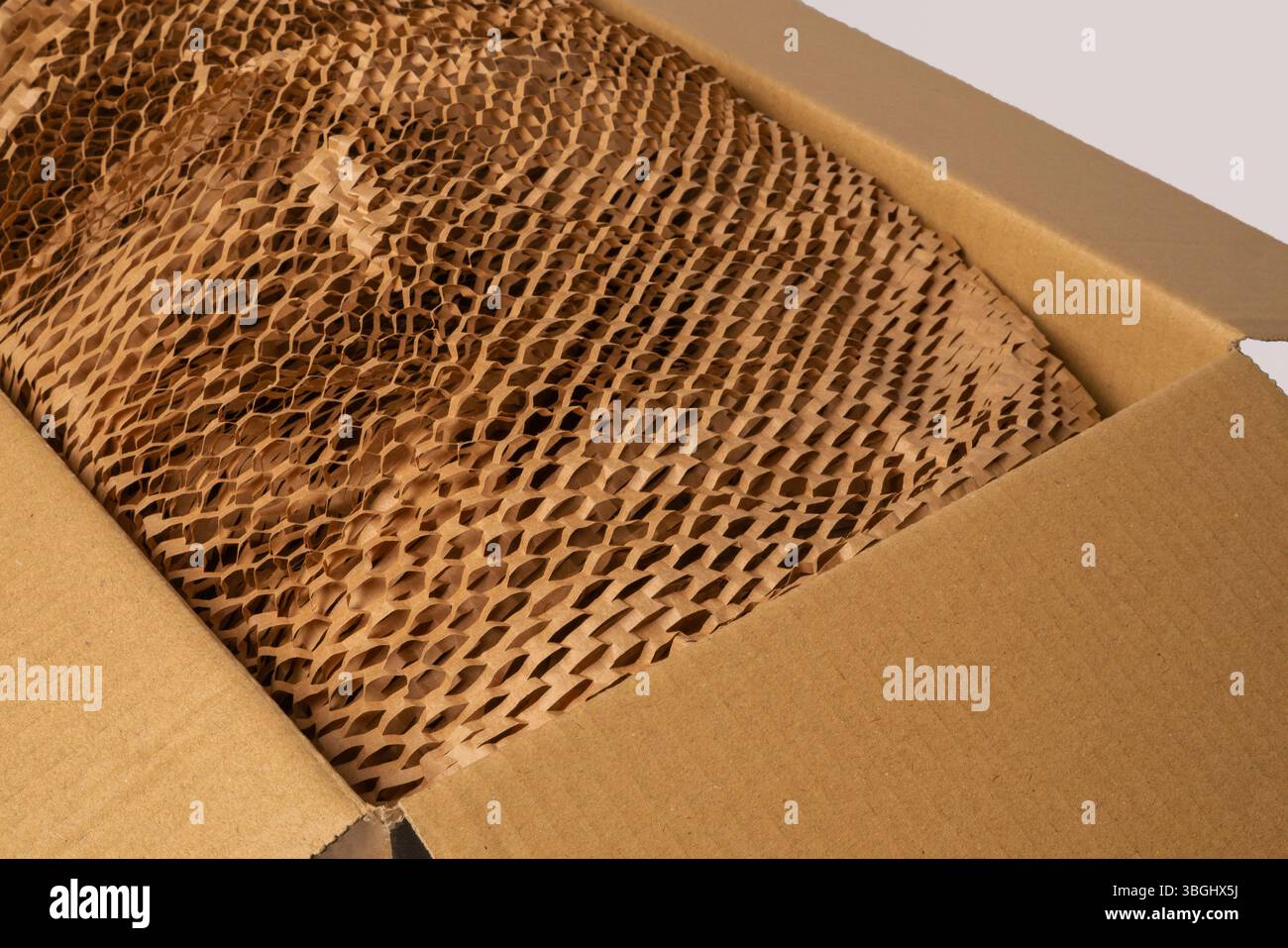 Scatola di cartone aperta con materiali riciclati ecologici, tra cui carta marrone e imbottitura a nido d'ape. Foto Stock