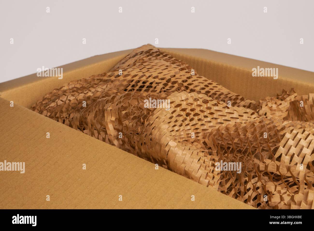 Scatola di cartone aperta con materiali di imballaggio riciclati ecologici, tra cui carta marrone e imbottitura a nido d'ape. Foto Stock