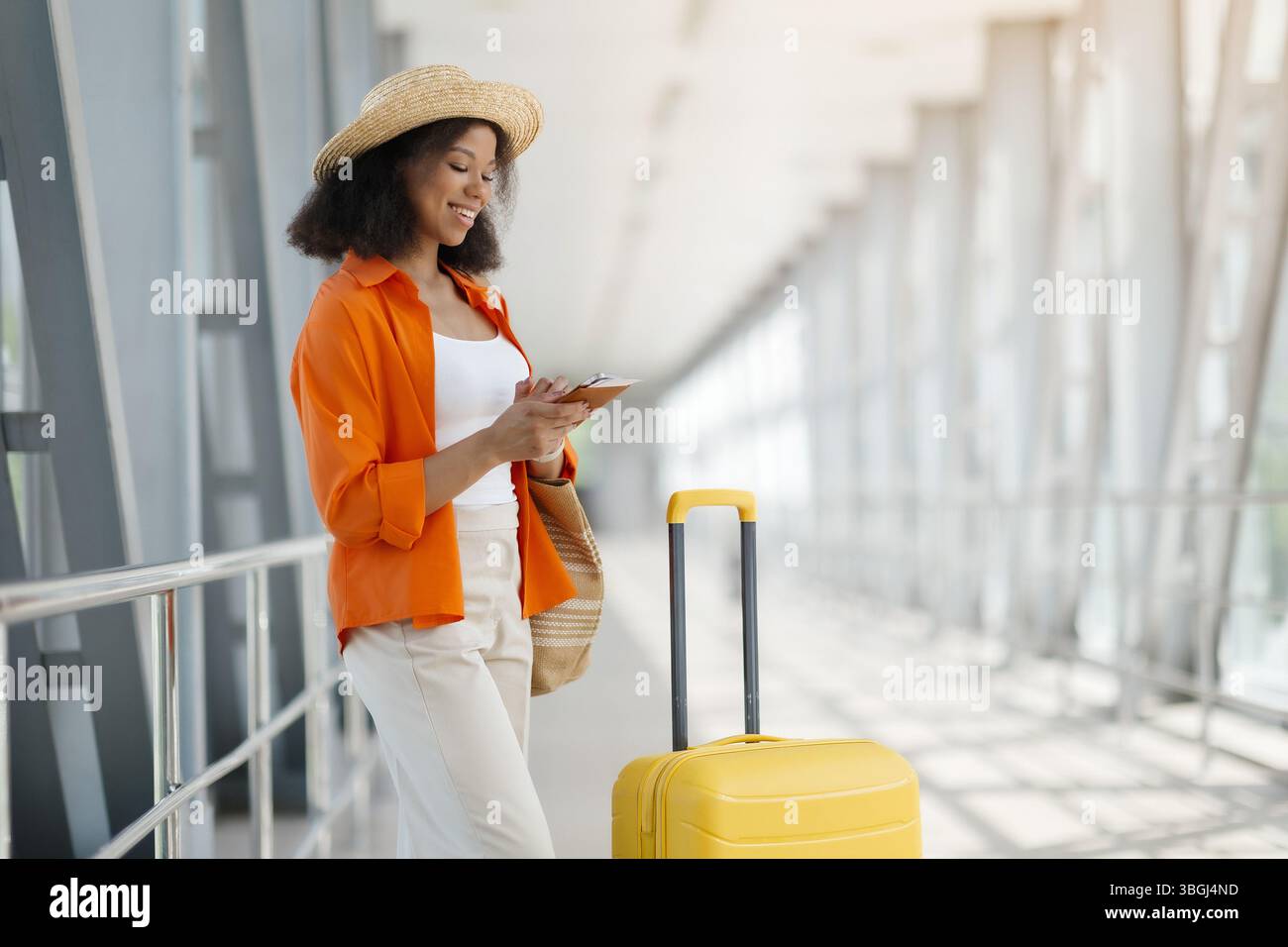 Ritratto della bella donna nera che usa lo smartphone mentre aspetta all'aeroporto Foto Stock