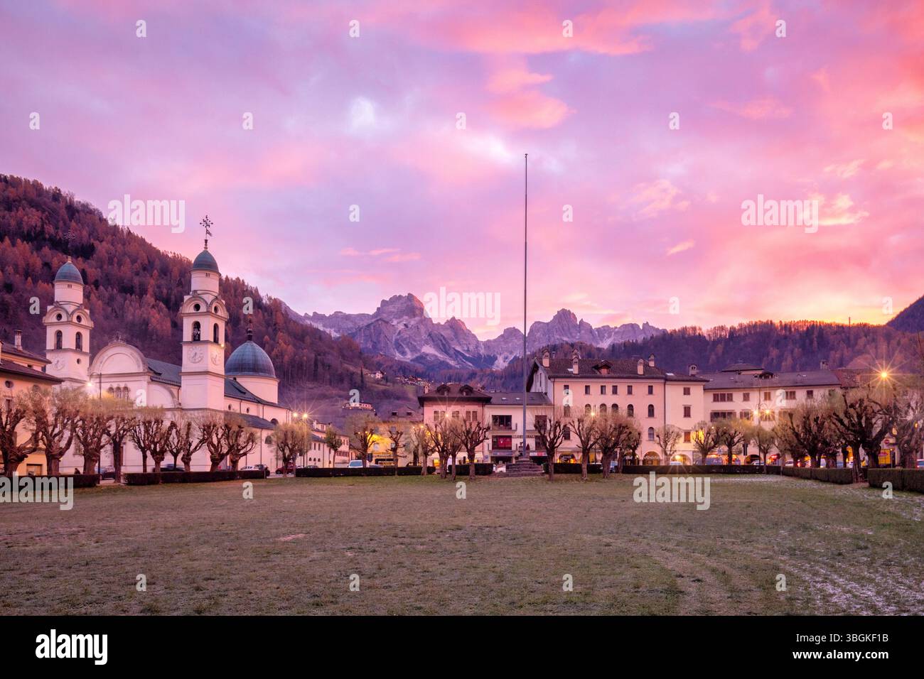 L'alba invernale su Agordo, con la sua chiesa parrocchiale e piazza sotto le vette dolomitiche del Tamer - San Sebastiano, provincia di Belluno, Veneto, Italia Foto Stock