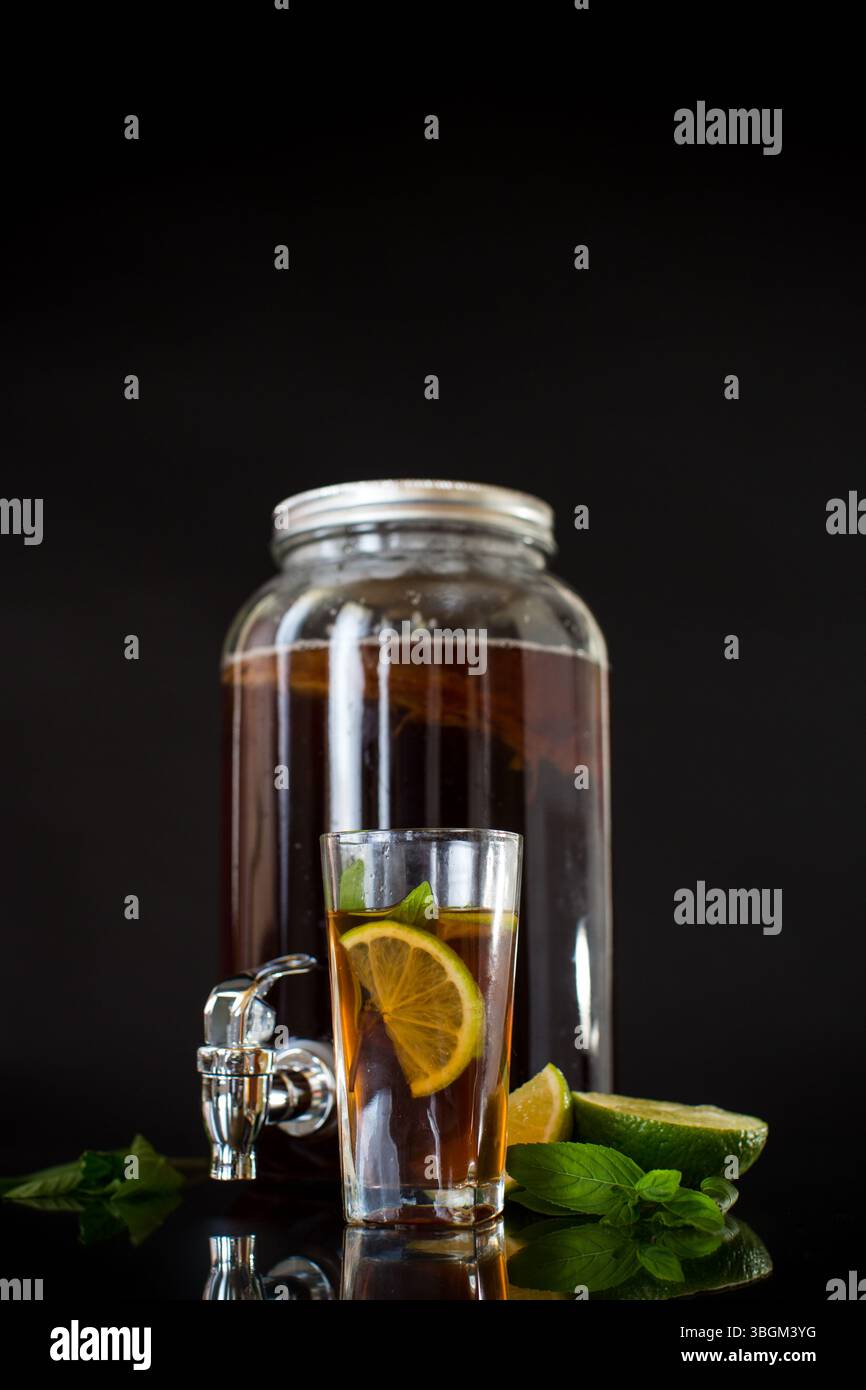 Kombucha rinfrescante in un vaso di vetro e un bicchiere con lime su sfondo nero. Foto Stock Kombucha rinfrescante in un vaso di vetro e un bicchiere con lime su sfondo nero. Foto Stock