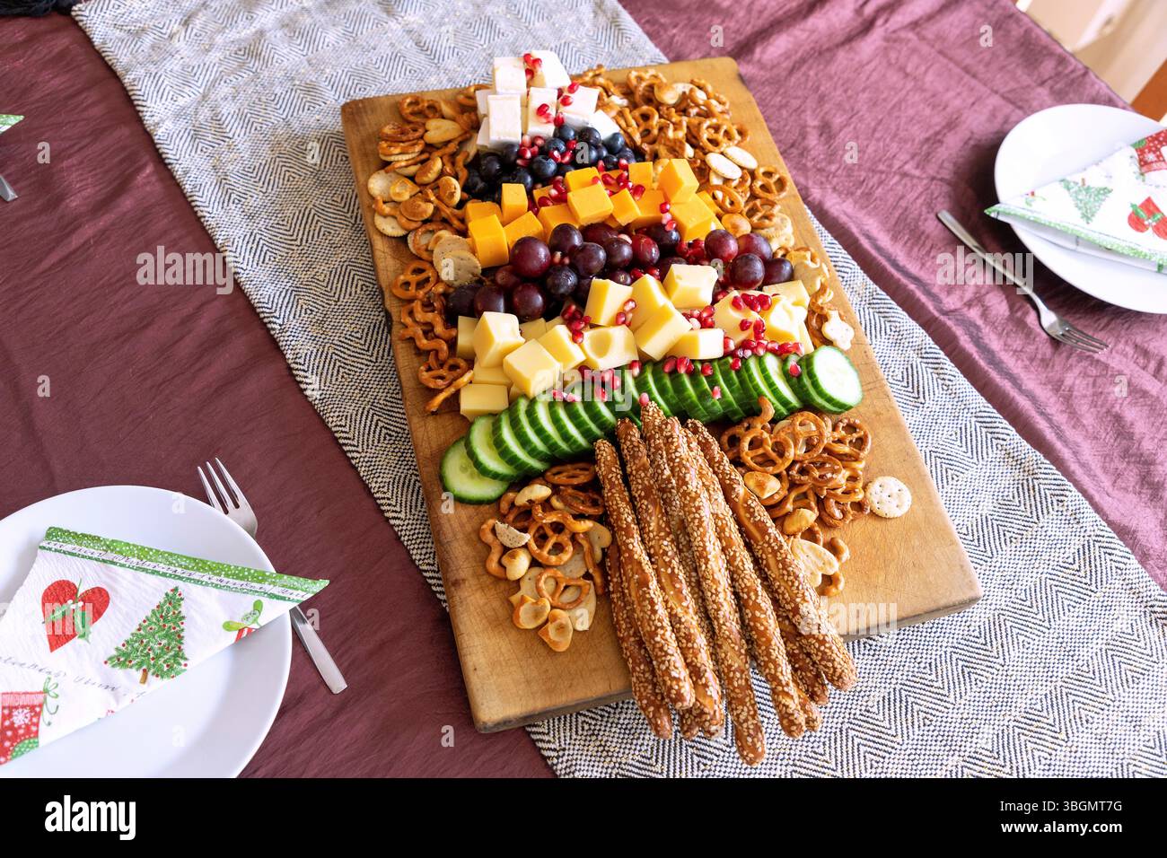 Vassoio di spuntini sull'albero di Natale con formaggio Emmental, Cheddar e Brie, con uva, mirtilli, cetriolo e semi di melograno, con pretzel salati e bastoncini di sesamo Foto Stock