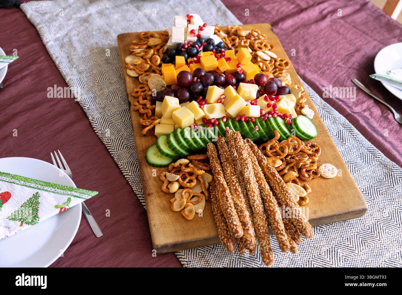 Vassoio di spuntini sull'albero di Natale con formaggio Emmental, Cheddar e Brie, con uva, mirtilli, cetriolo e semi di melograno, con pretzel salati e bastoncini di sesamo Foto Stock