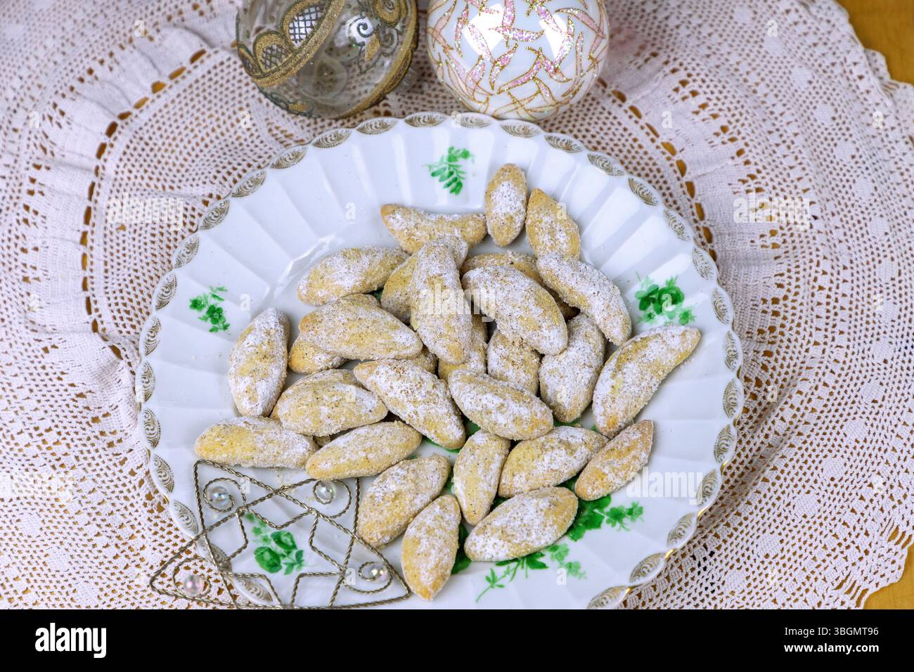 Mezzaluna di vaniglia, con baule natalizie e stelle decorative su una tovaglia di pizzo Foto Stock