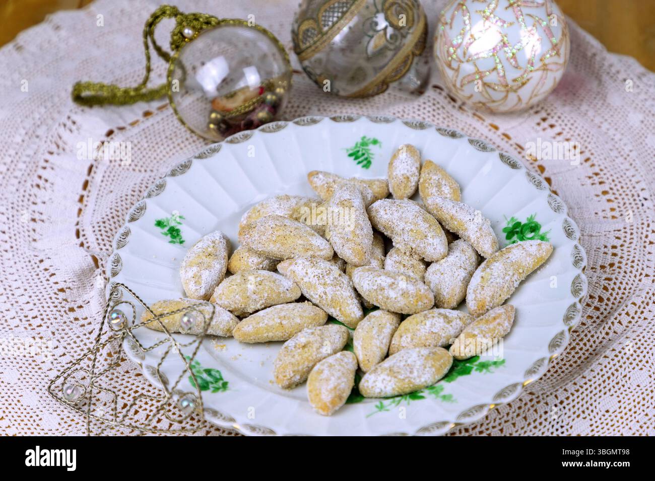 Mezzaluna di vaniglia, con baule natalizie e stelle decorative su una tovaglia di pizzo Foto Stock