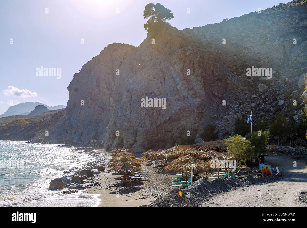 Spiaggia di sabbia e ciottoli Spiaggia Embros Thermes e piscina termale sull'isola di Kos in Grecia retroilluminata Foto Stock