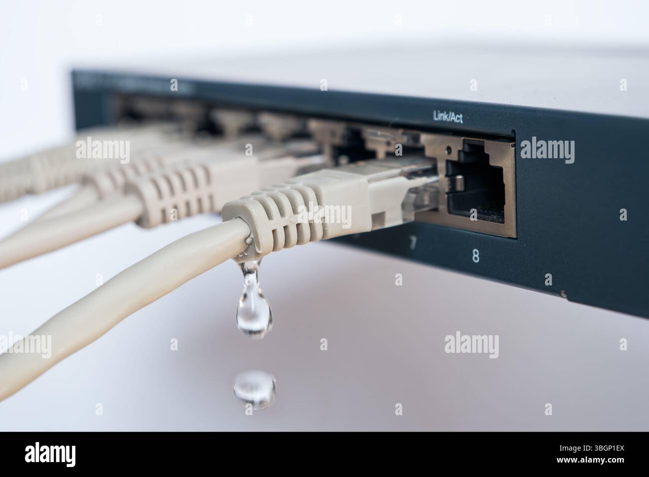 Uno switch Ethernet con gocciolamento d'acqua da un cavo di rete: Rappresentazione simbolica di perdite di dati, cyber spionaggio e attacchi di hacker alle aziende Foto Stock