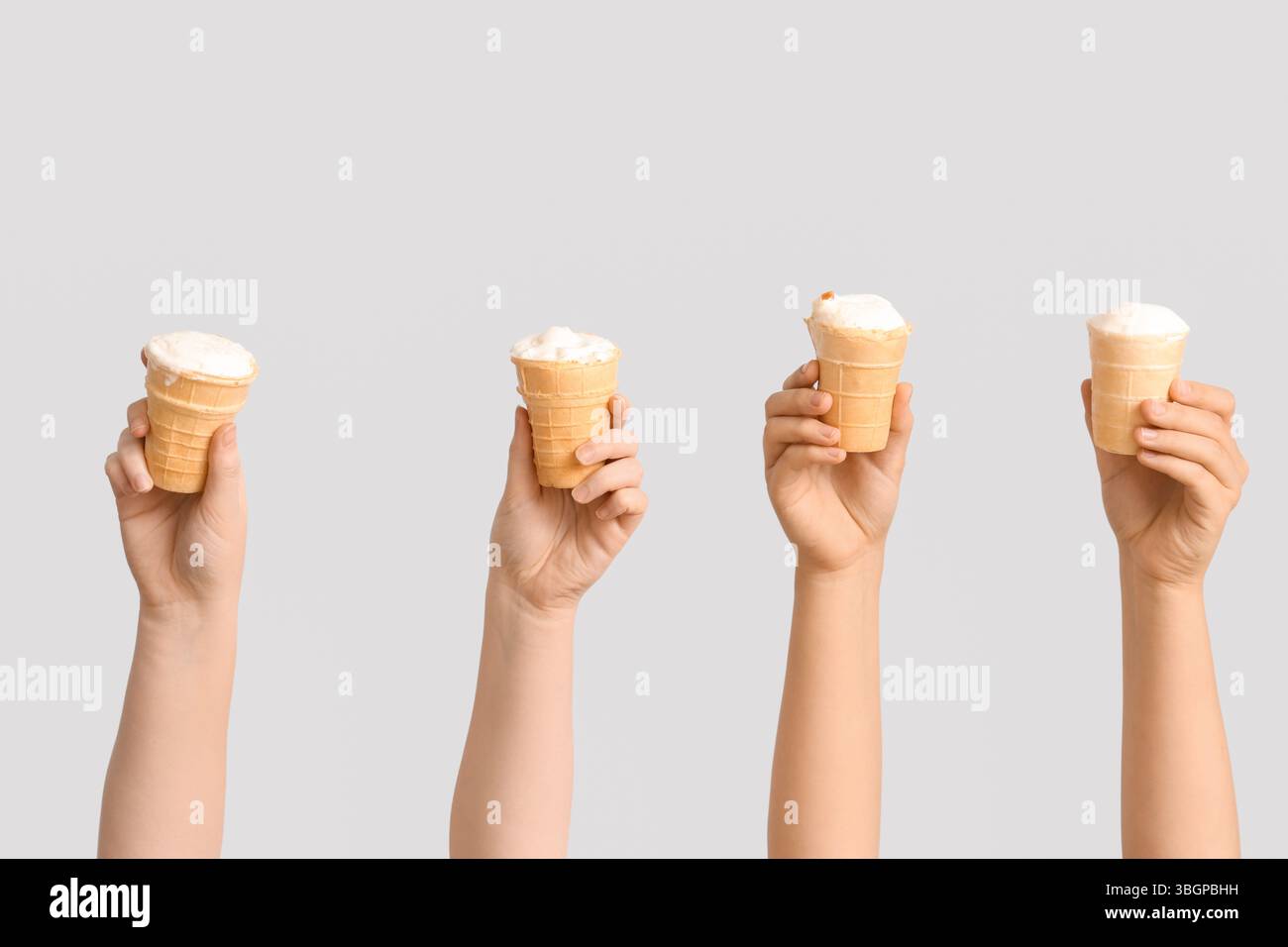 Mani femminili con gelato dolce in cialde su sfondo grigio Foto Stock