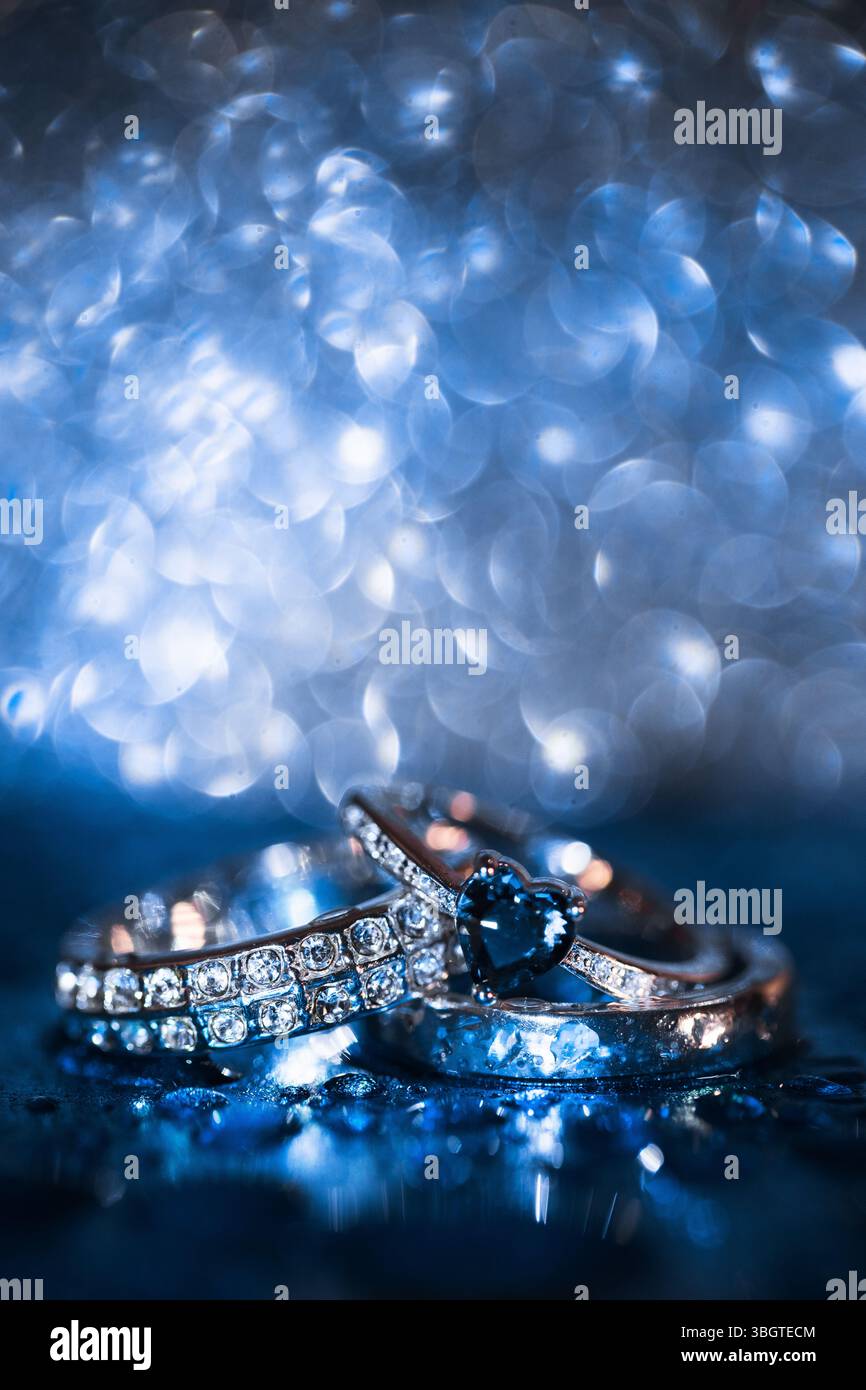 Due fedi nuziali dorate splendidamente disposte su una superficie blu testurizzata in stile minimalista, per creare un'atmosfera pulita, emotiva e di alto livello Foto Stock