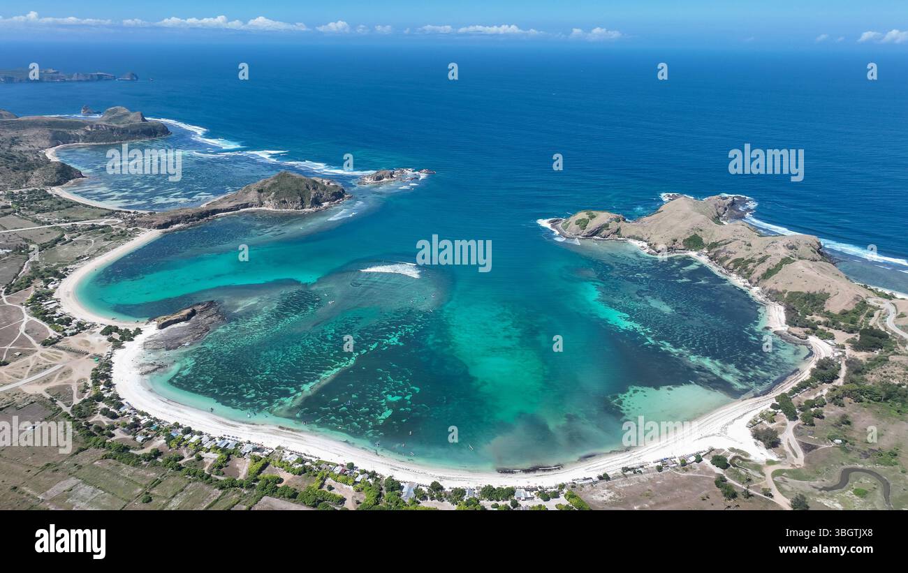 Vista aerea della baia turchese di Lombok incorniciata da promontori spettacolari e sabbia bianca. L'acqua cristallina rivela le vivaci barriere coralline sotto la superficie. Foto Stock