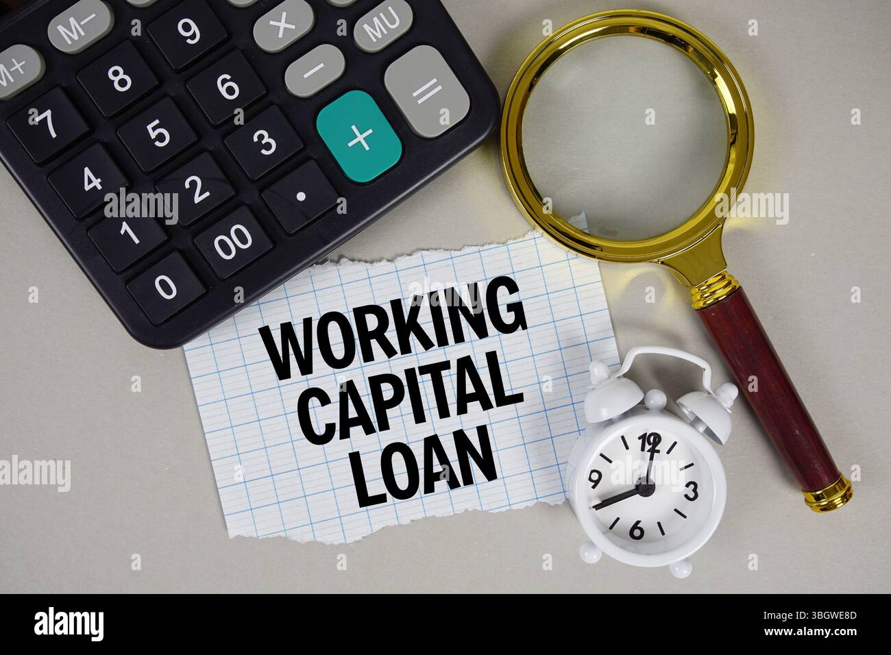 Testo prestito capitale circolante con sveglia, calcolatrice anc in vetro ingrandente su sfondo grigio Foto Stock