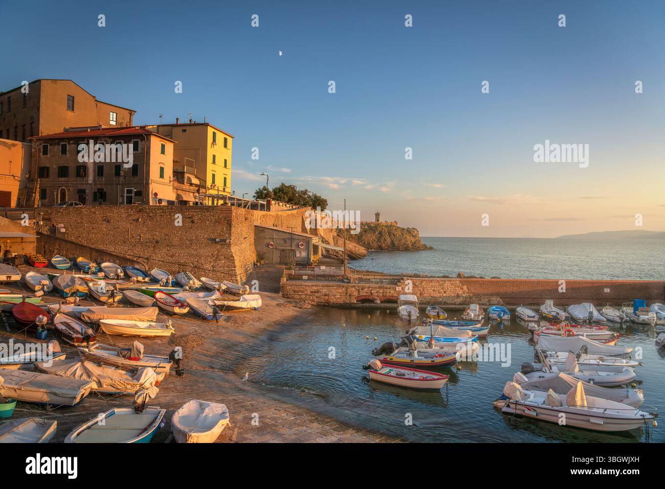 Tramonto sul lungomare di Piombino e barche nel porticciolo. Seascape in Maremma, Toscana, Italia Foto Stock