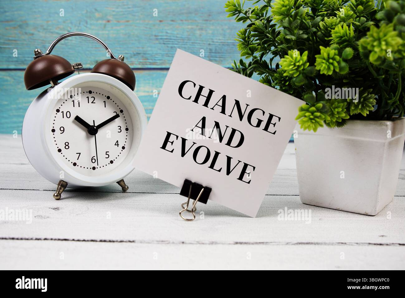 Modificare ed evolvere il testo scritto su carta con sveglia su sfondo in legno Foto Stock