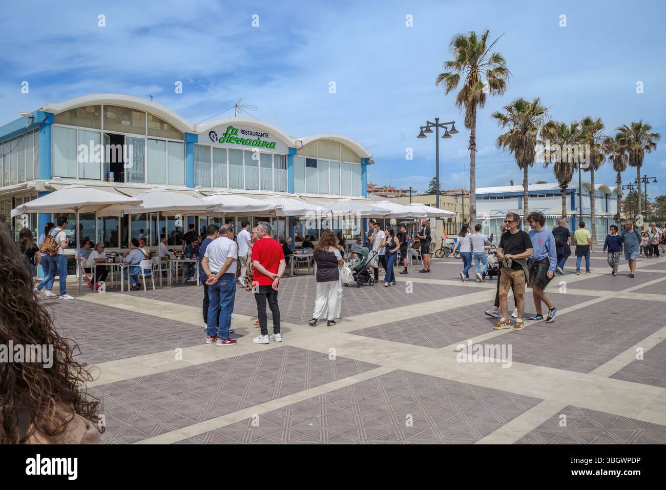 Vivace ristorante fronte spiaggia presso Malvarrosa Beach Valencia Spagna. Ristoranti costieri, palme lungo il lungomare, vivace atmosfera estiva, viaggi e.. Foto Stock