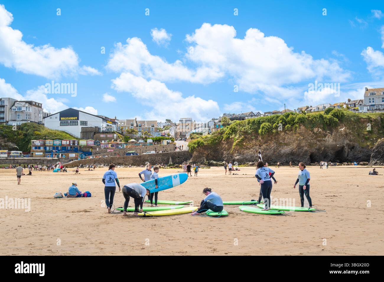 Un gruppo di principianti di surf che si preparano per una lezione di surf con un istruttore della scuola di surf SSS a Towan Beach a Newquay in Cor Foto Stock