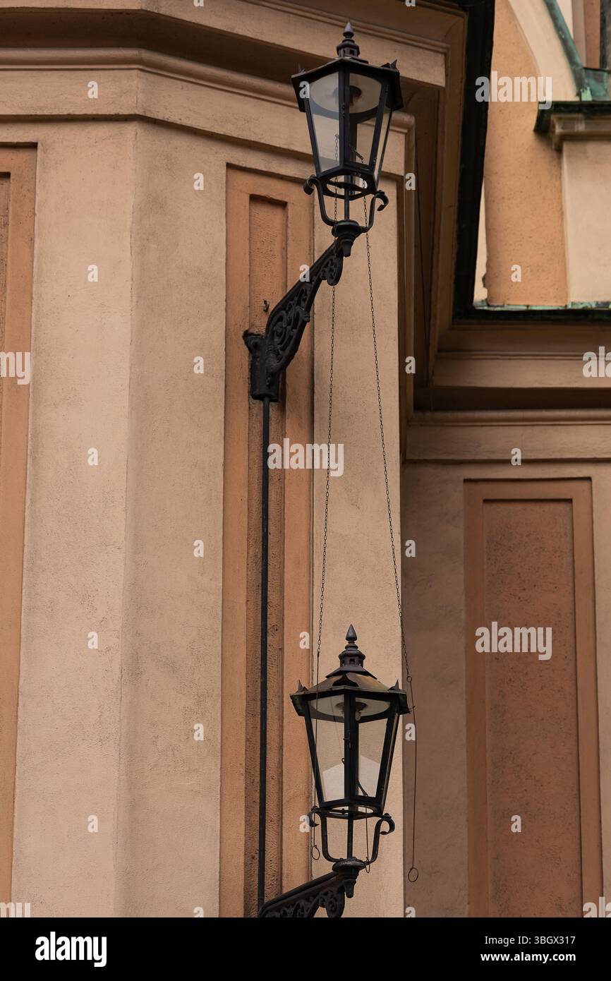Lanterne in ferro battuto d'epoca con catene decorative montate sulla facciata di un edificio storico con stucchi e dettagli architettonici Foto Stock