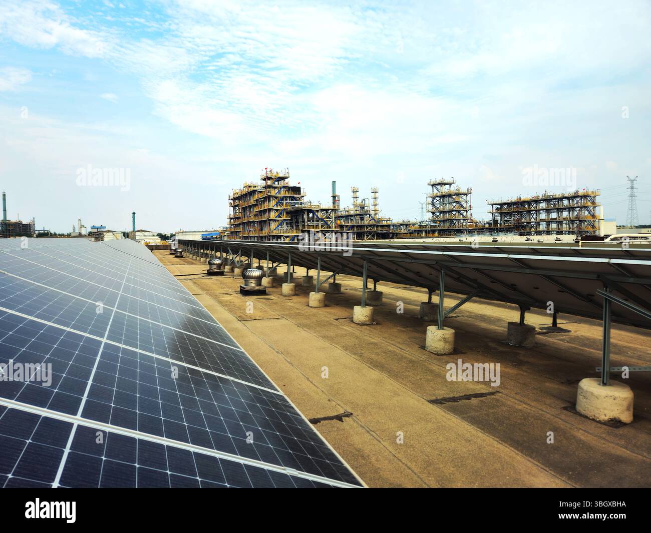 Pannelli solari adiacenti all'impianto petrolchimico - paesaggio industriale di transizione energetica Foto Stock