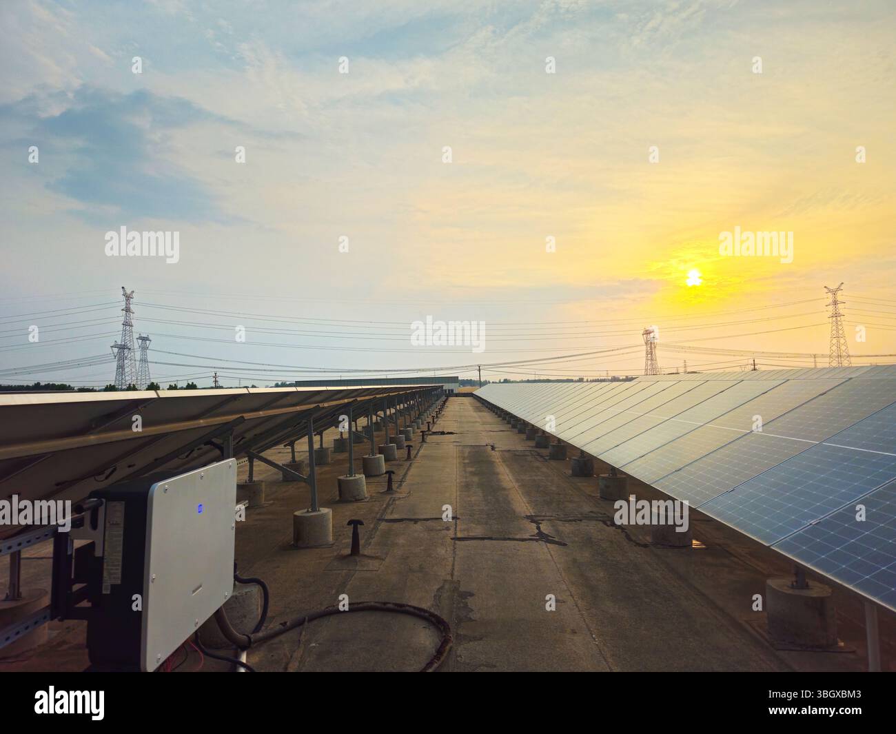 Solar Photovoltaic Array and Transmission Towers at Sunset, Renewable Energy Infrastructure Foto Stock
