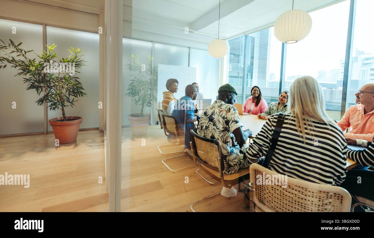 Un gruppo diversificato di professionisti in una riunione collaborativa all'interno di un grazioso e moderno studio d'ufficio. Lo spazio luminoso e aperto è stato progettato per ispirare il creat Foto Stock