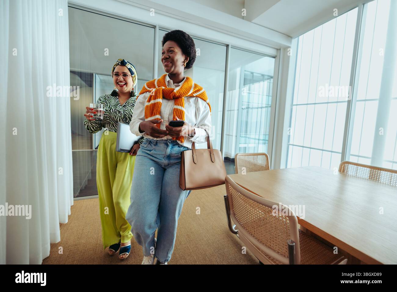 Due gioiose donne d'affari lasciano il lavoro il venerdì pomeriggio, mostrando un senso di libertà e sollievo. La scena cattura la loro vibrante espressione Foto Stock