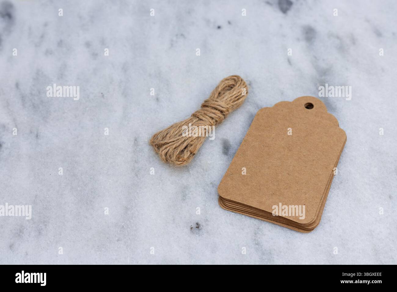 Etichette regalo in carta vuota con spago su superficie in marmo con spazio vuoto per testo Foto Stock