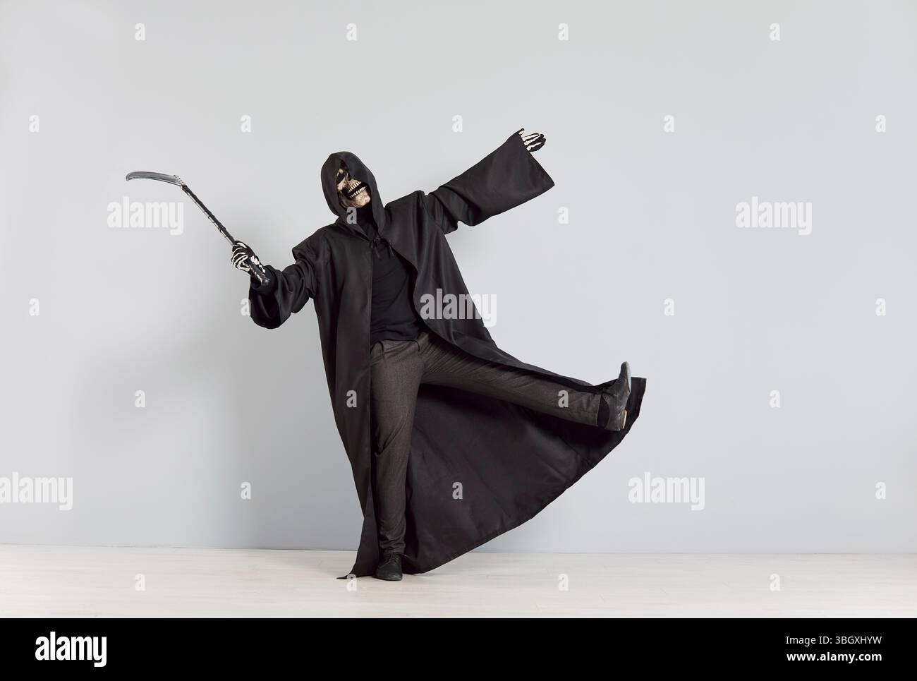 Persona sconosciuta in costume di Halloween che rappresenta la morte pone in modo spettacolare con la falce nella mano destra Foto Stock