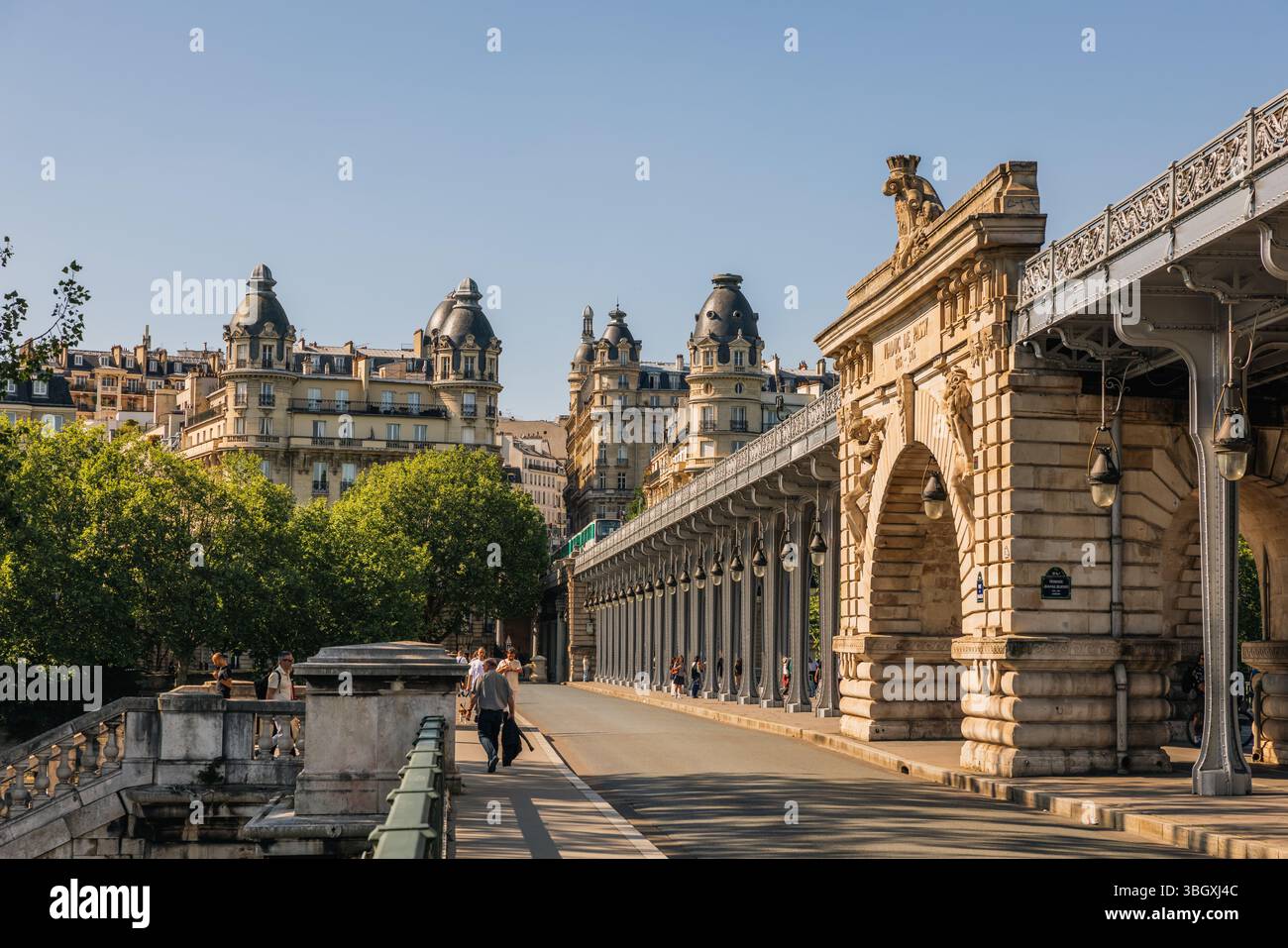 Una vista panoramica lungo l'iconico Pont de Bir-Hakeim a Parigi, mostrando la sua struttura unica a due livelli e le persone che si godono una passeggiata in una giornata di sole con i clas Foto Stock