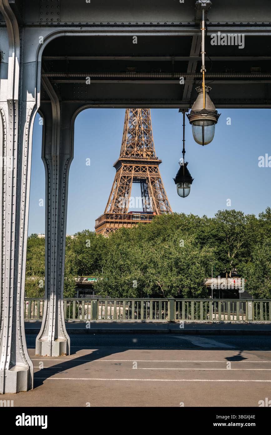 Un'iconica vista verticale della Torre Eiffel a Parigi, incorniciata ad arte dall'architettura industriale in acciaio e dalle lampade del ponte Pont de Bir-Hakeim. Foto Stock