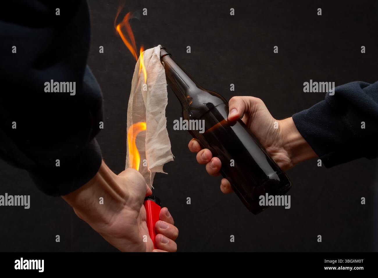 Un uomo accende un panno in una bottiglia, accendendo un cocktail molotov Foto Stock