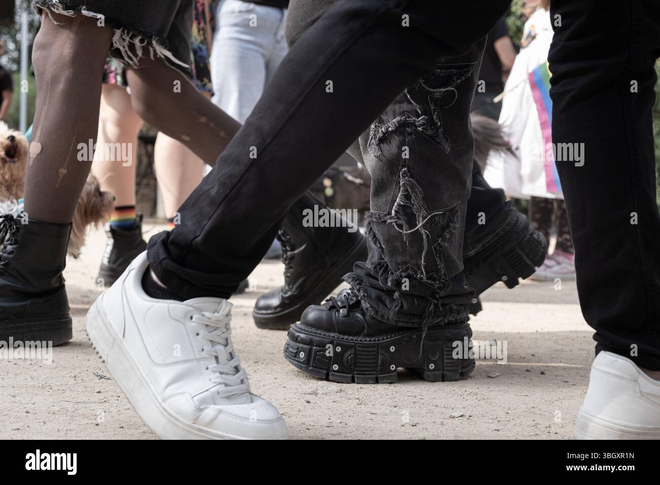 Gambe e scarpe di persone che camminano in una sfilata gay Pride, mostrando diversi stili di calzature, jeans strappati e orgoglio lgbt Foto Stock