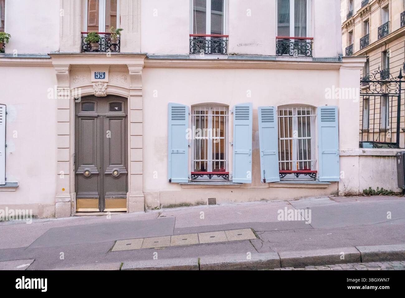 Una classica facciata di un edificio parigino caratterizzato da una doppia porta grigia (numero 55) e due finestre con persiane aperte di colore azzurro. L'edificio si trova su Foto Stock