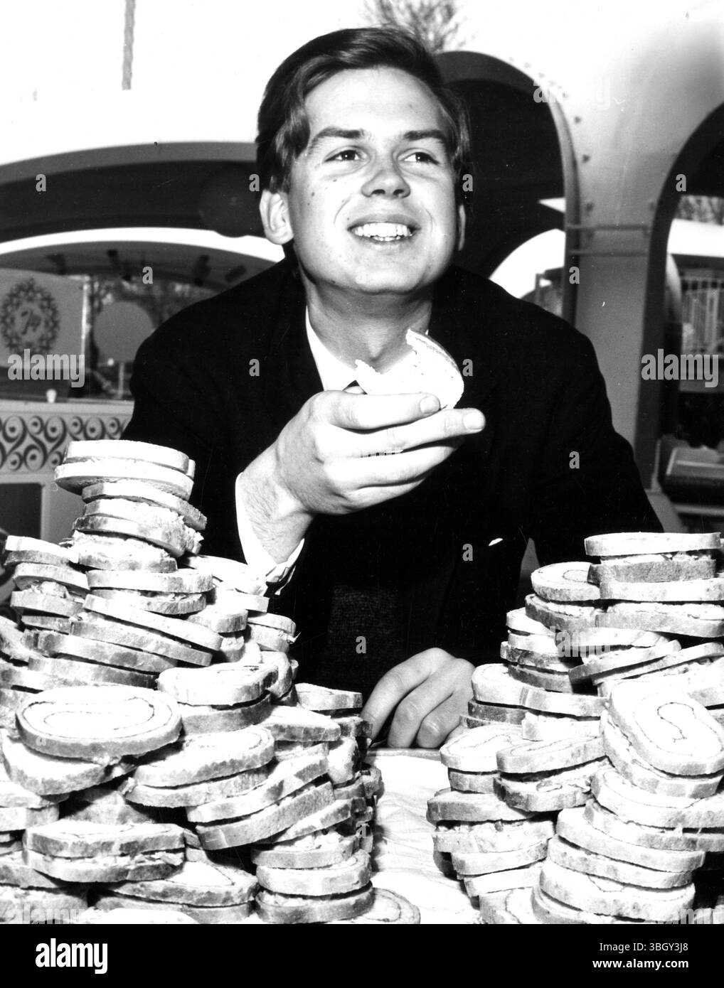 Il futuro conte di Sandwich (John Montagu di Gran Bretagna) sembra essere all'altezza del suo nome mentre prepara dei panini seduto dietro una vera montagna di loro all'International Garden come Fiera Mondiale. 21 aprile 1964 Foto Stock