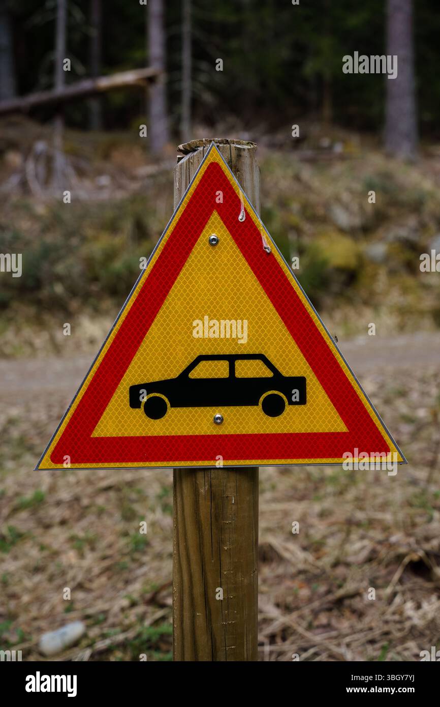 Segnale di avvertimento giallo del veicolo accanto a una strada forestale nella natura selvaggia. Foto Stock